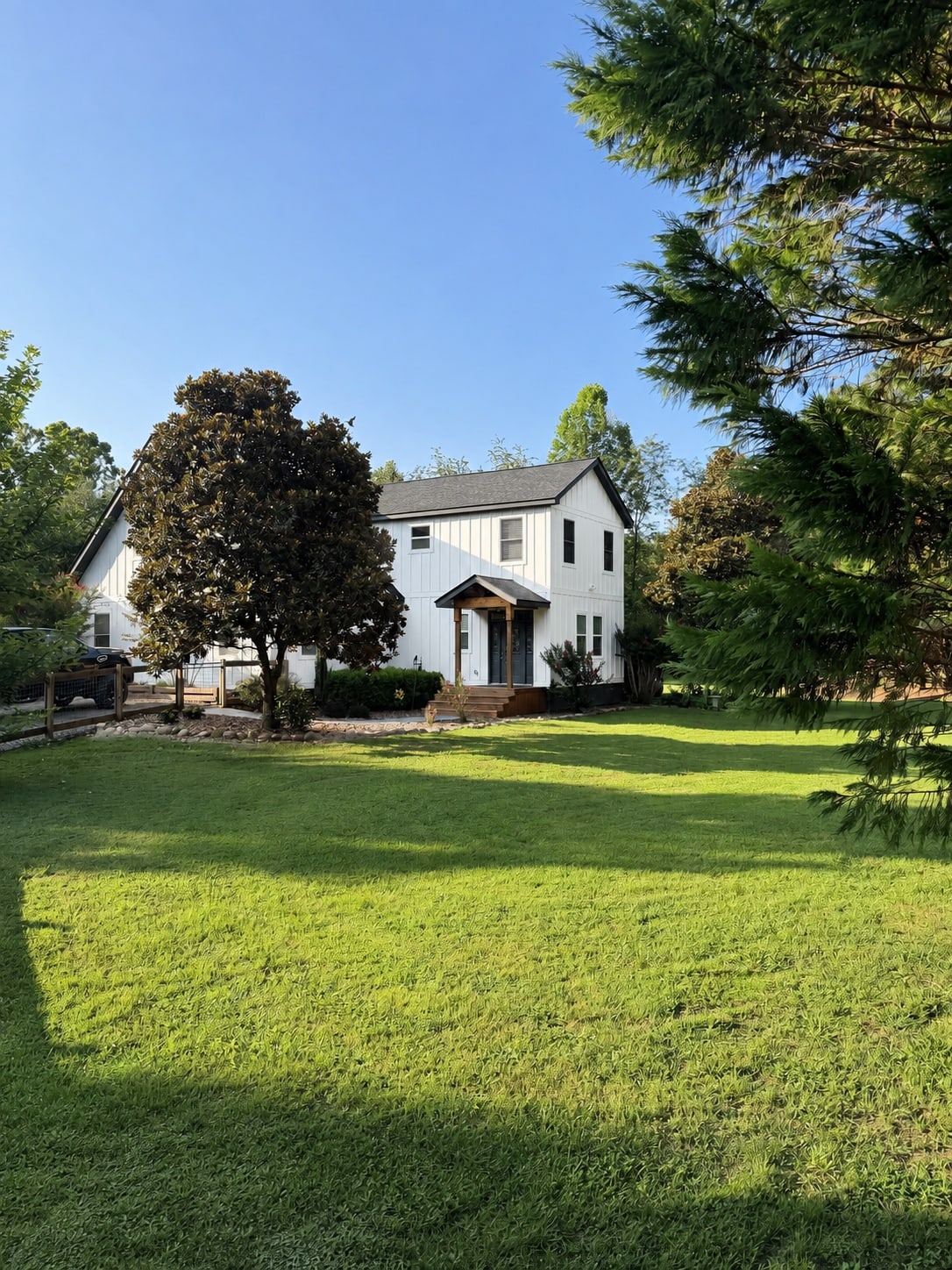 Front of the white two-story home framed by mature trees