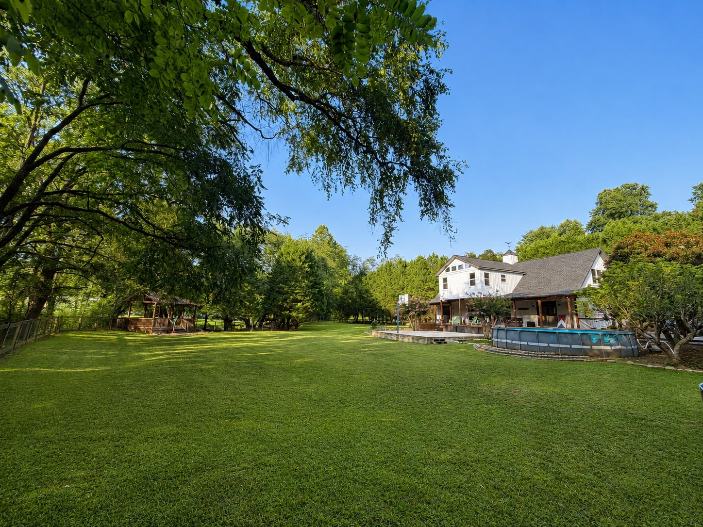 Wide view of the home, lawn, pool, basketball court, and gazebo
