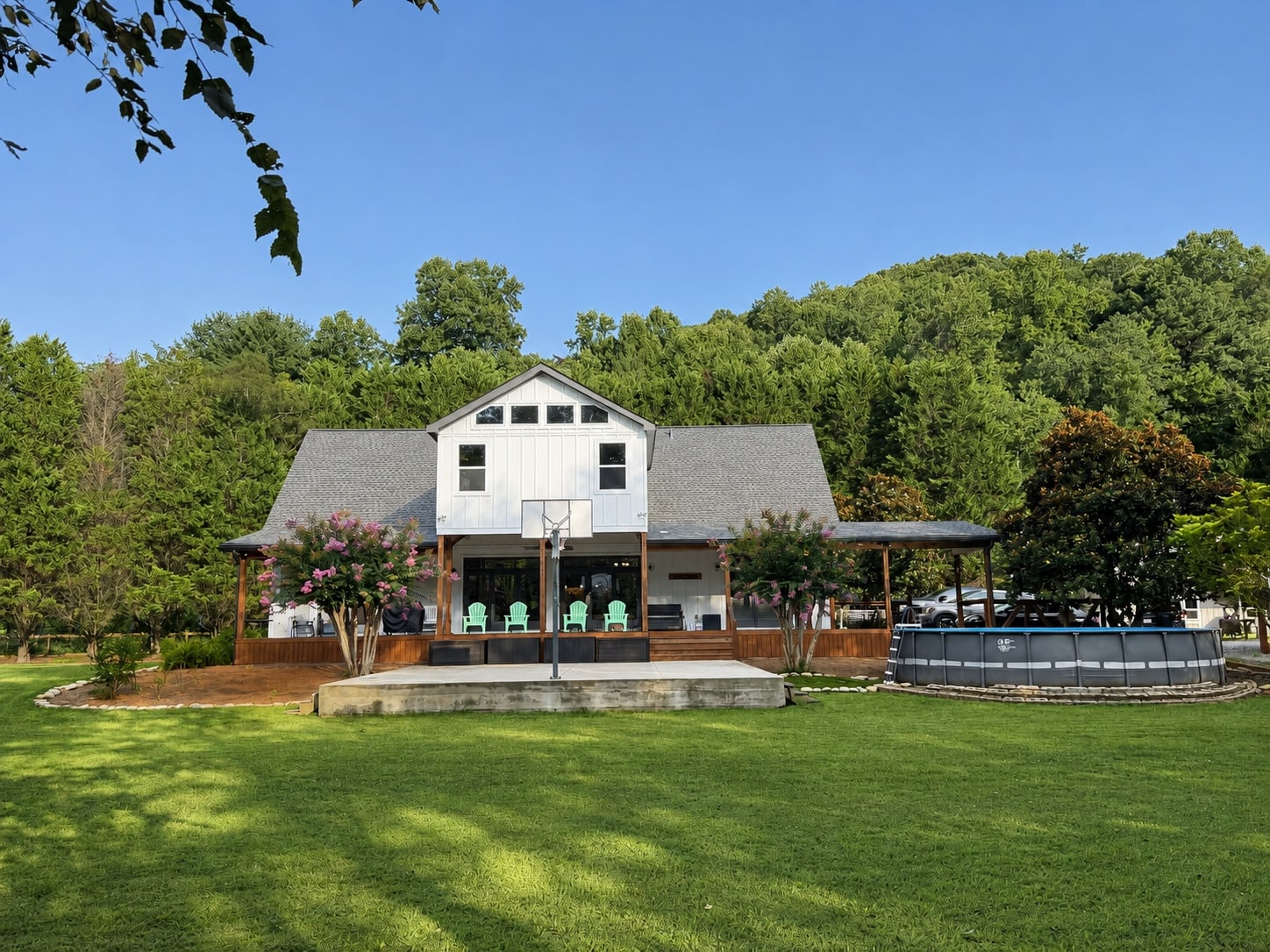 Rear elevation of the home with covered porch, pool, and basketball court