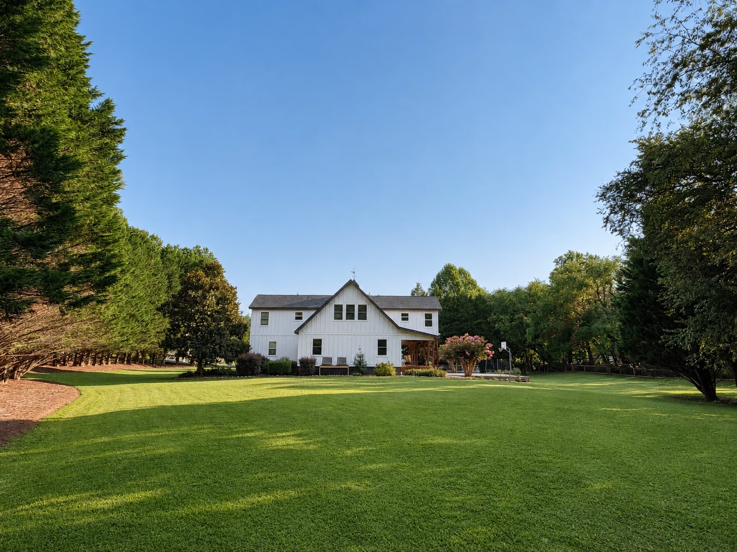 White two-story home seen across a broad green lawn