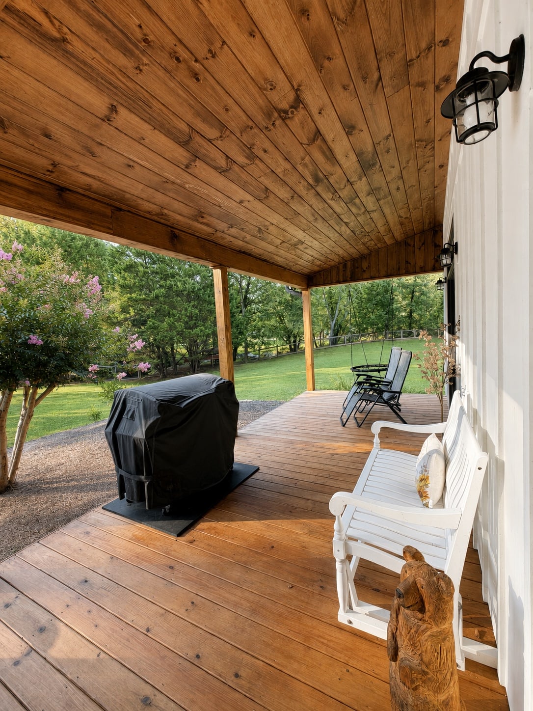 Outdoor seating beneath the covered porch beside the lawn
