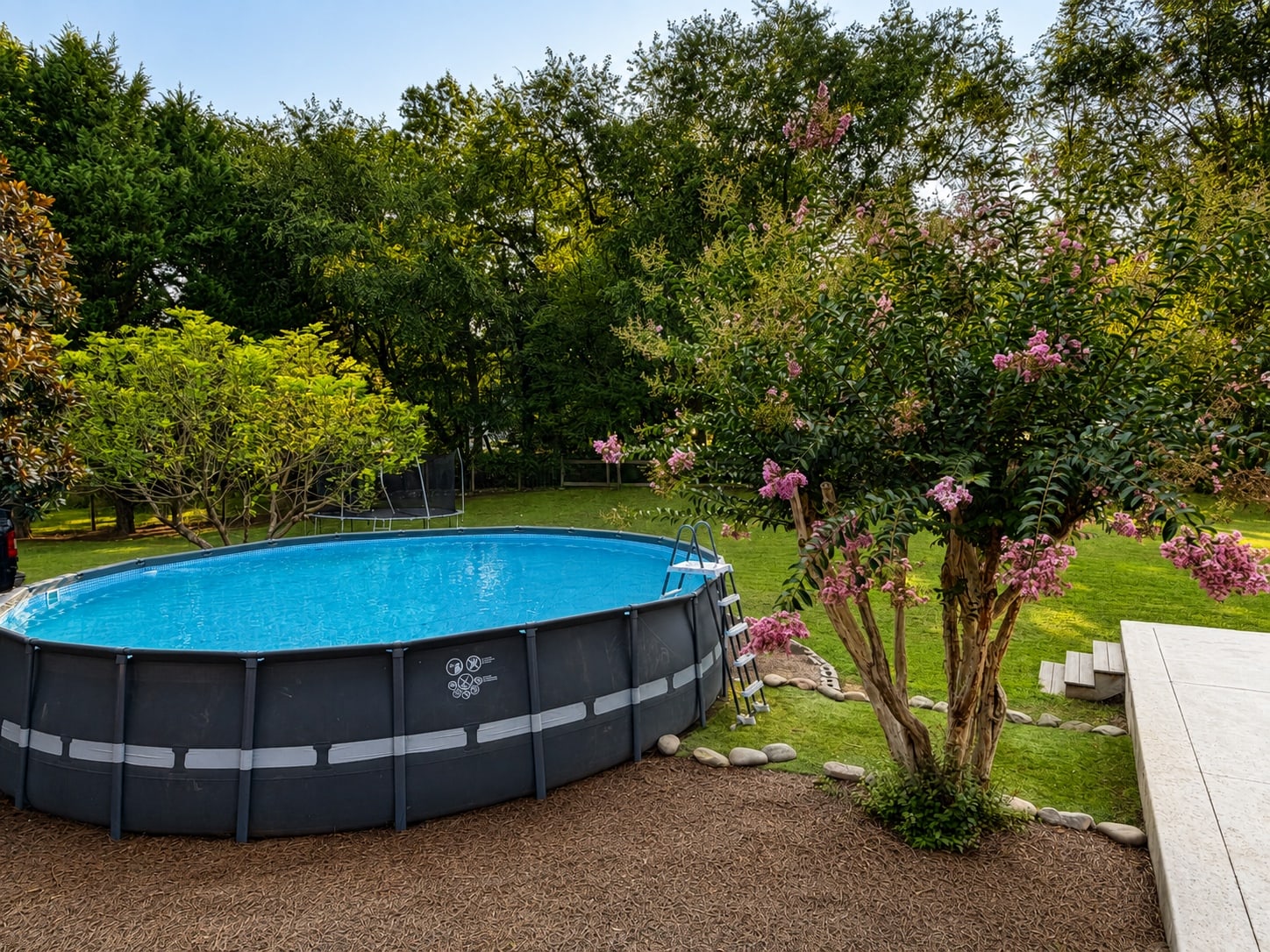 Above-ground swimming pool surrounded by established landscaping