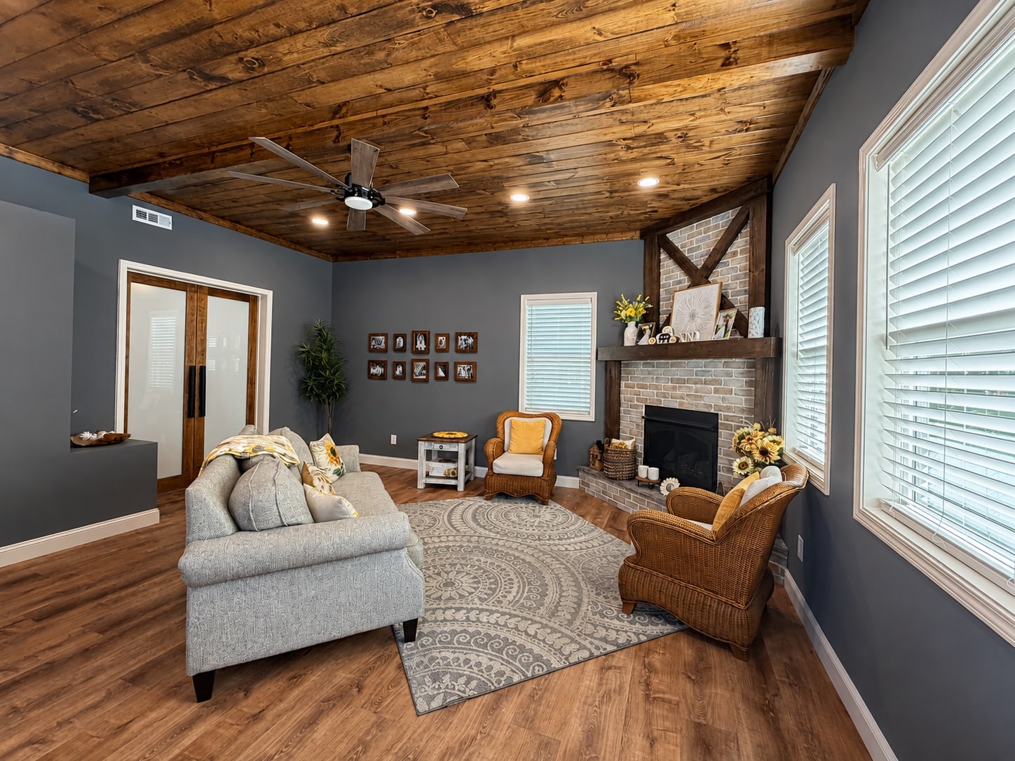 Living room with wood ceiling, large windows, and brick fireplace
