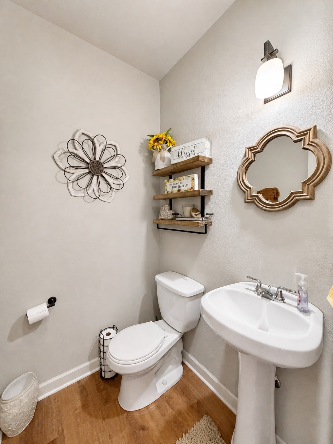 Powder room with pedestal sink, mirror, and wood-look flooring