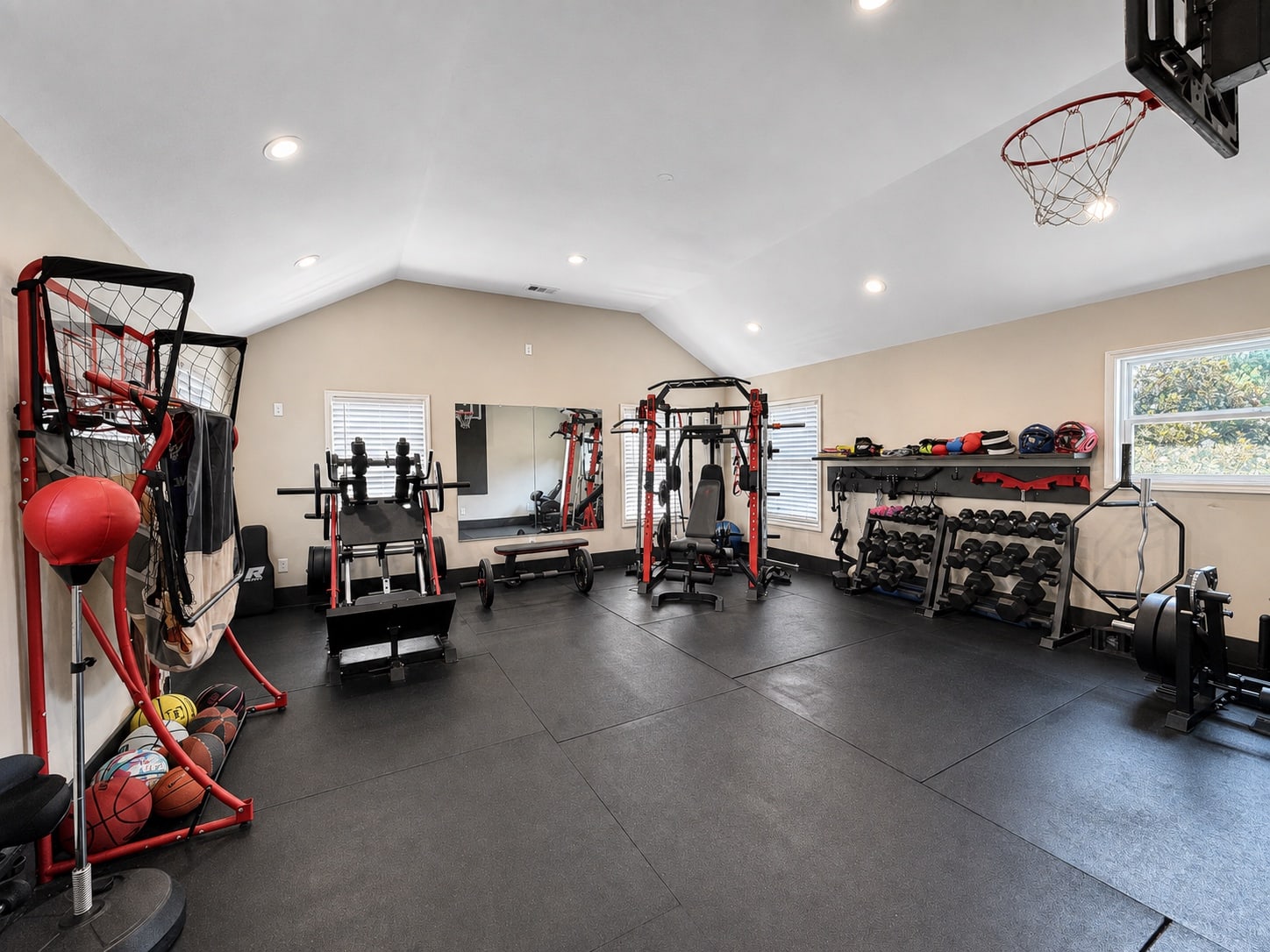 Spacious home gym with weight equipment and indoor basketball hoop