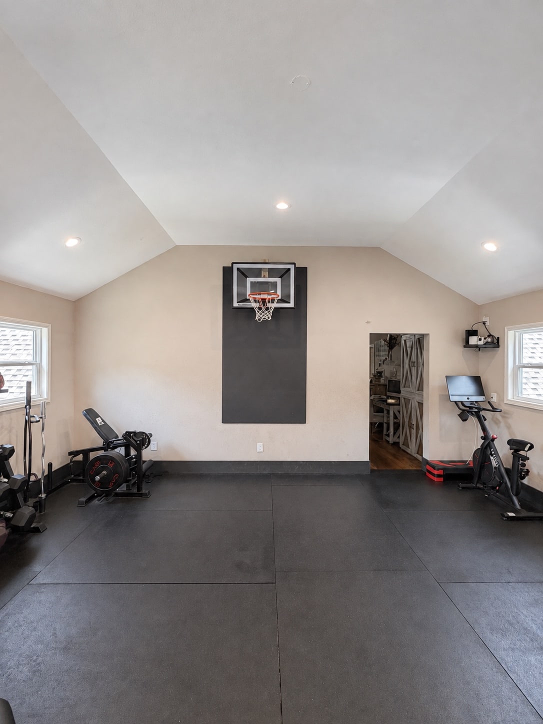 Home gym with exercise bike, weights, and indoor basketball hoop