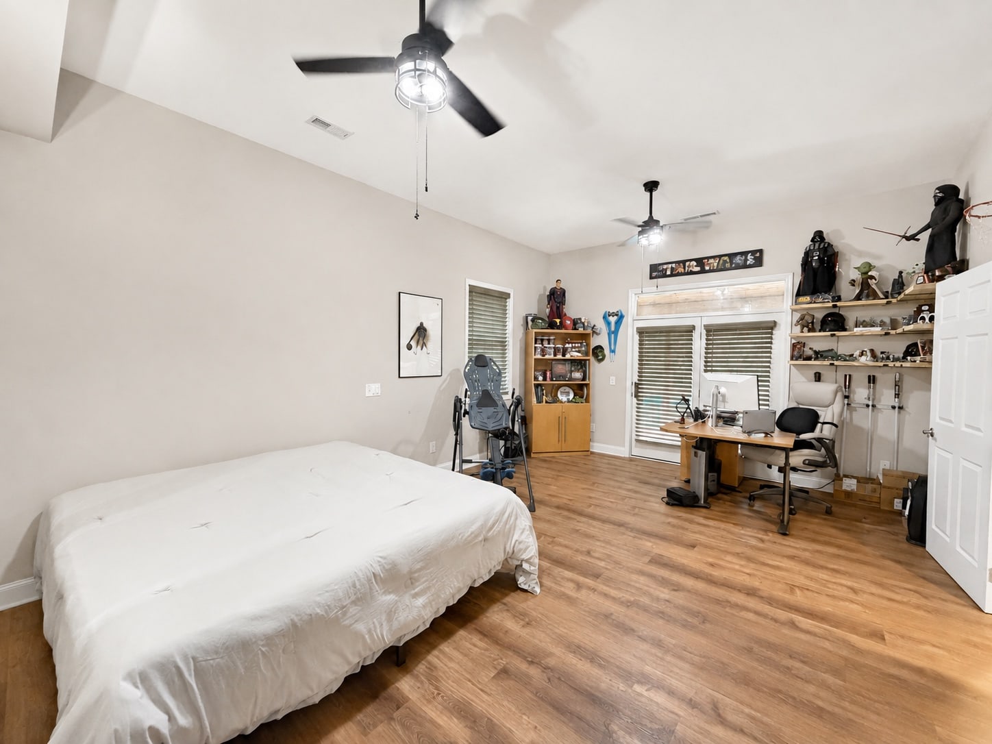 Large bedroom with office area, wood-look flooring, and French doors