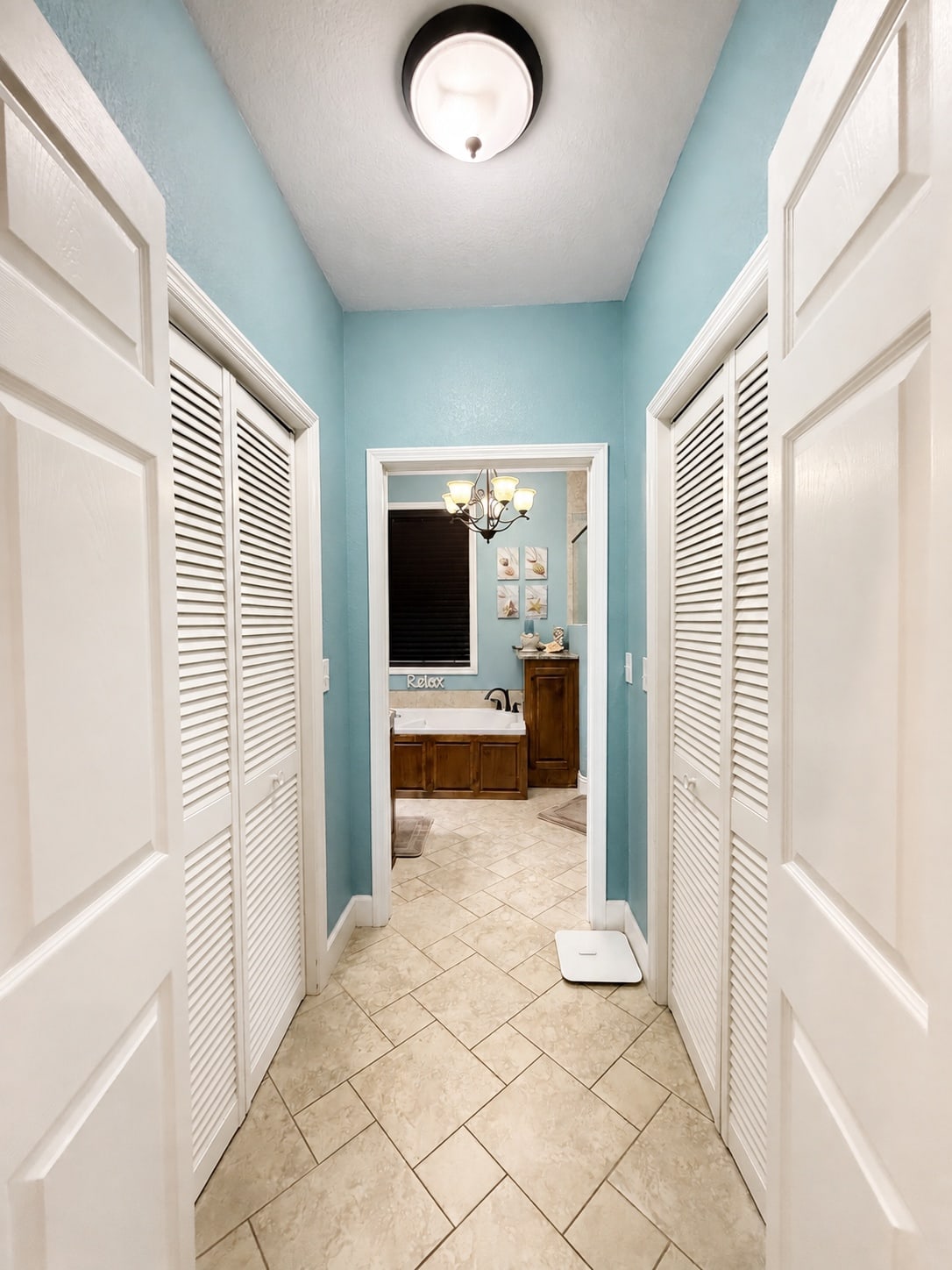 Blue hallway with dual closets leading into the primary bathroom