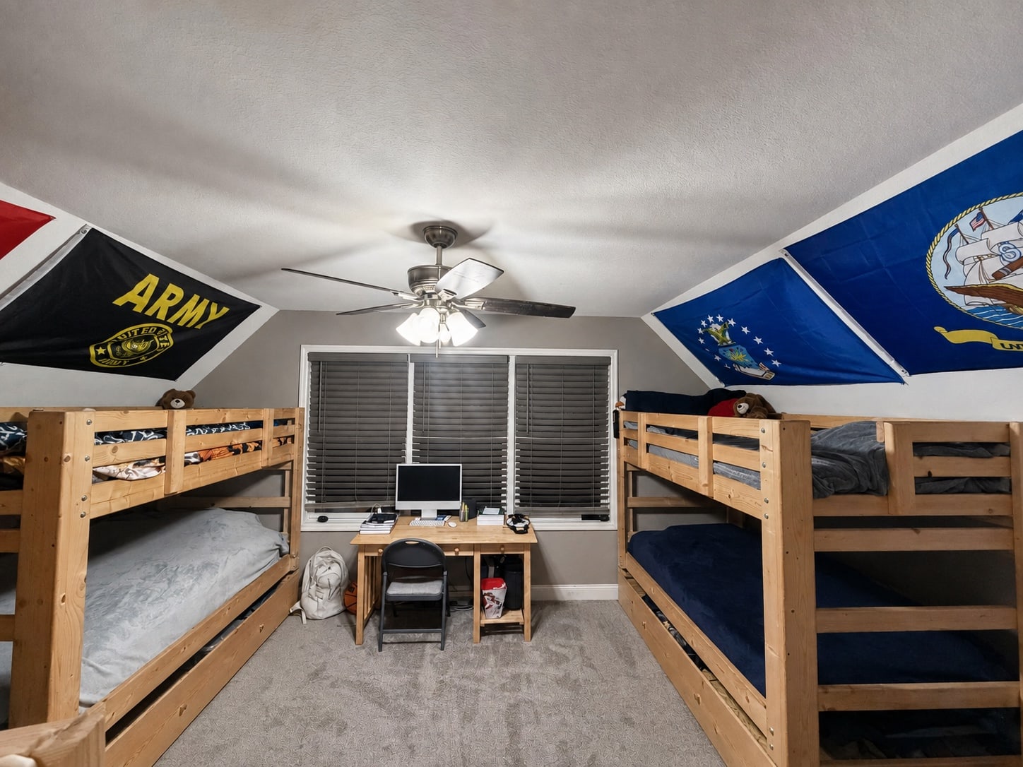 Bedroom arranged with two bunk beds and a central study desk