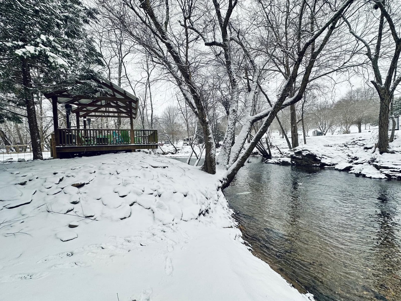 Covered riverside gazebo and trees blanketed in fresh snow