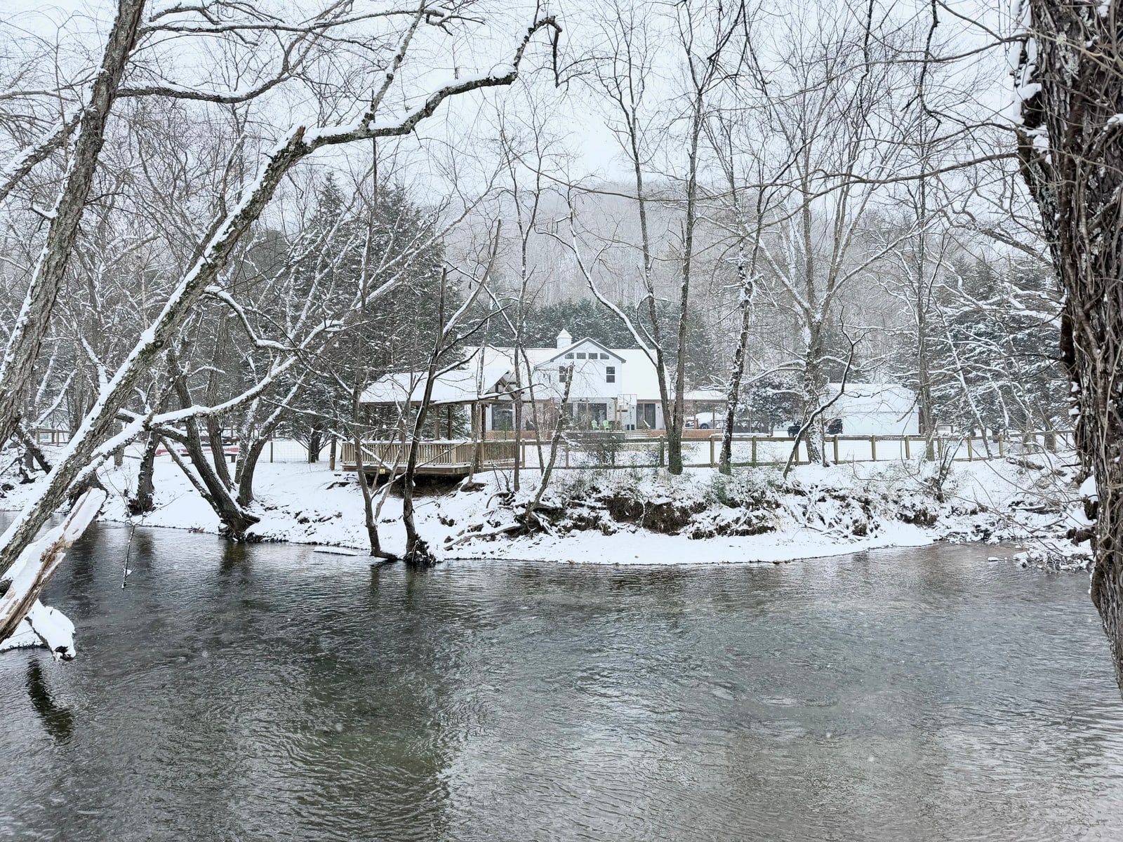 The home and gazebo seen across the flowing river in winter